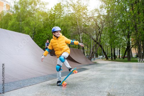a child rides a blue city cruiser, a plastic bright skateboard, in a skate park on a halfpipe  © Ruslan Russland