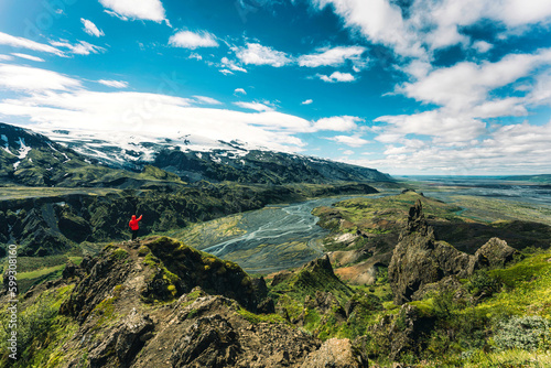 Hiker man in red jacket standing on top of Valahnukur surrounded by volcanic mountain and Krossa river in Icelandic Highlands at Thorsmork photo