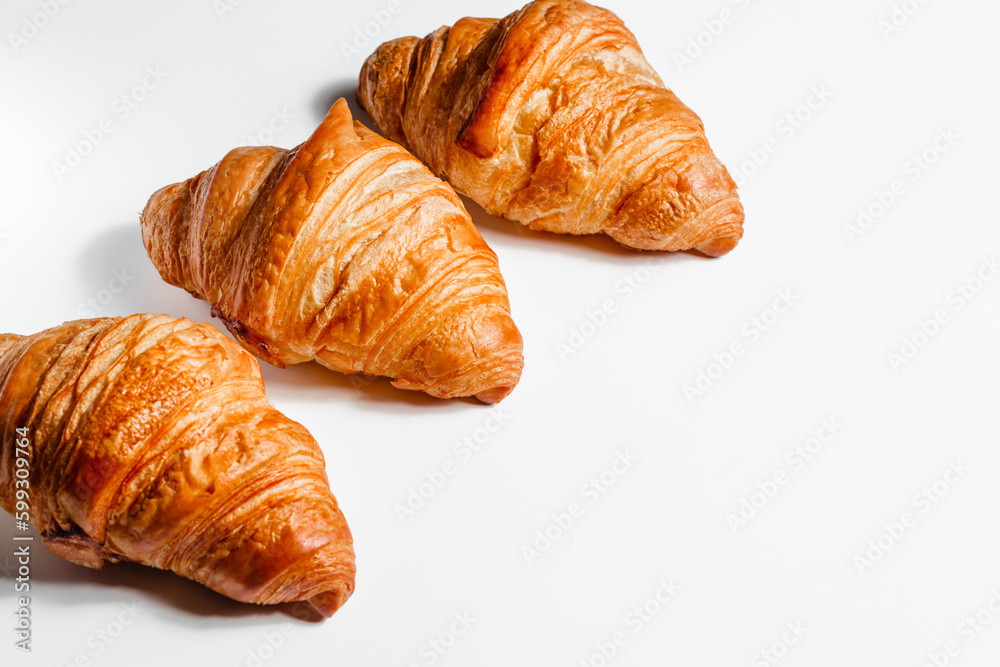 Three large croissants on a white background with space for text. Fresh pastries in butter. Creative concept for bakery and cafe