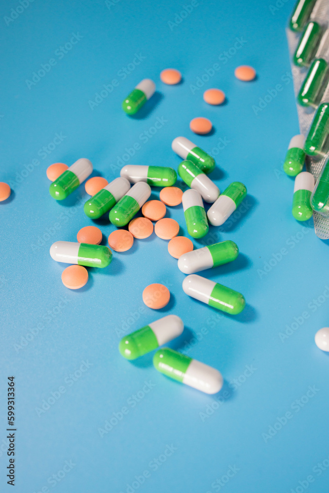 Assorted pharmaceutical medicine pills, tablets and capsules on a blue background. Treatment concept