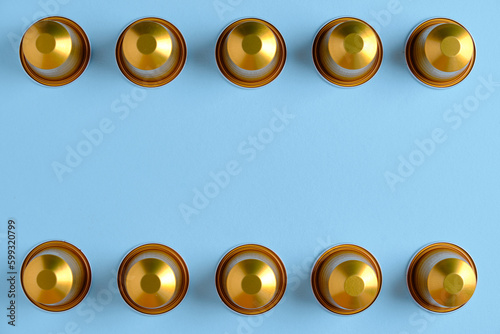 Gold coffee pods in a row against a plain background. Top down view.