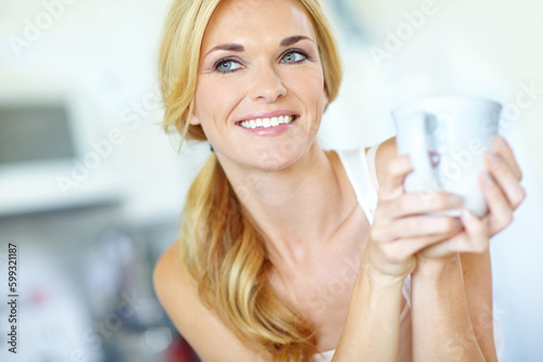 She enjoys a fresh cup of coffee. Attractive young blonde woman enjoying a delicious freshly-brewed cup of coffee.