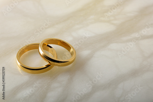 Gold wedding rings lying on white marble elevated view