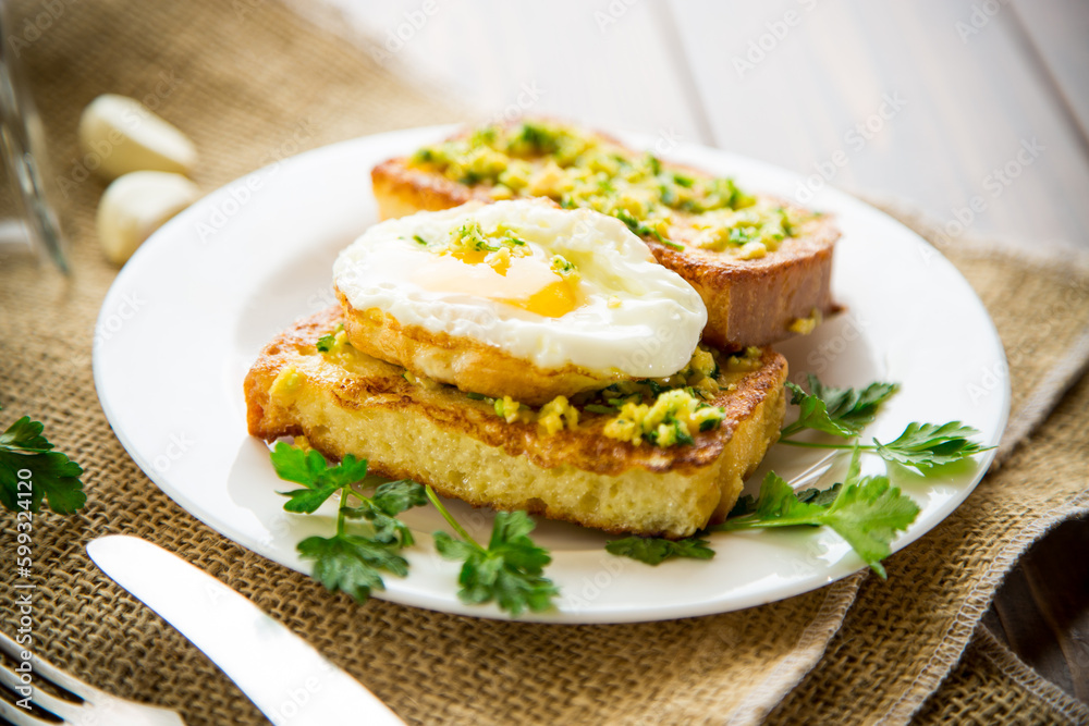 Fried croutons in batter with garlic and herbs and a fried egg in a plate. Fried croutons in batter with garlic and herbs and a fried egg in a plate.