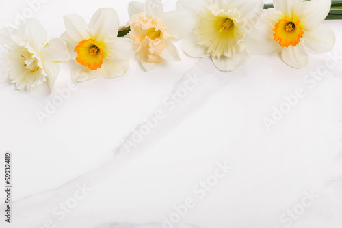 Flowers composition oh white marble background with spring daffodil flowers.