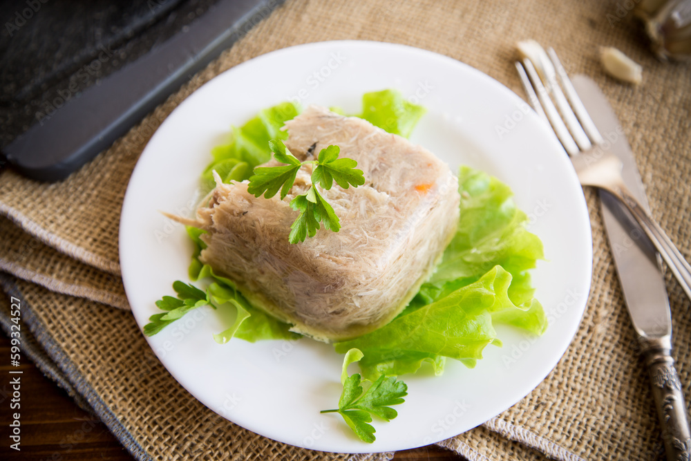 Boiled chicken meat aspic in meat gelatin broth in a plate Boiled chicken meat aspic in meat gelatin broth in a plate