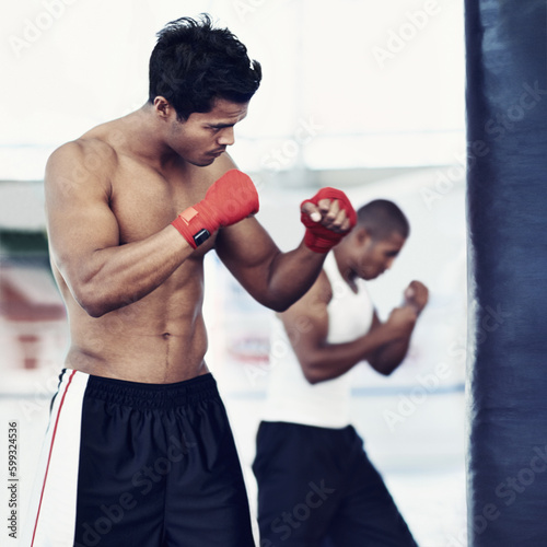 Hes dedicated to the sport of boxing. a young male boxers training on heavy bags.