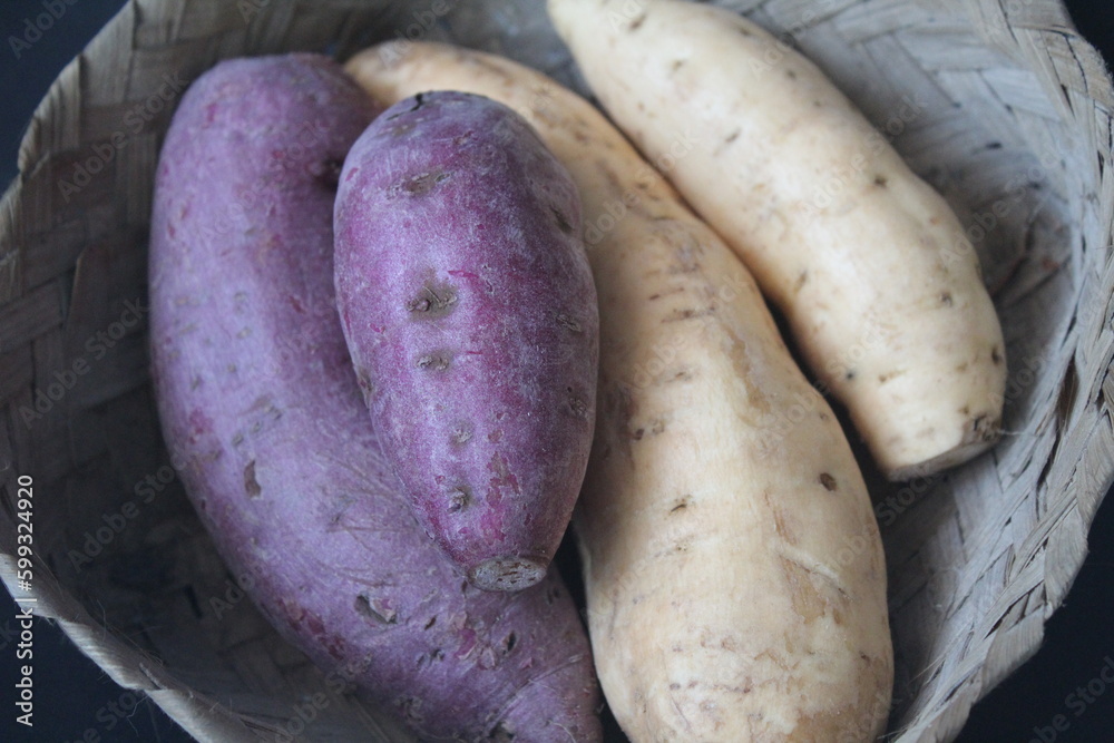 purple sweet potato and raw regular sweet potato in a bamboo basket purple sweet potato and raw regular sweet potato in a bamboo basket