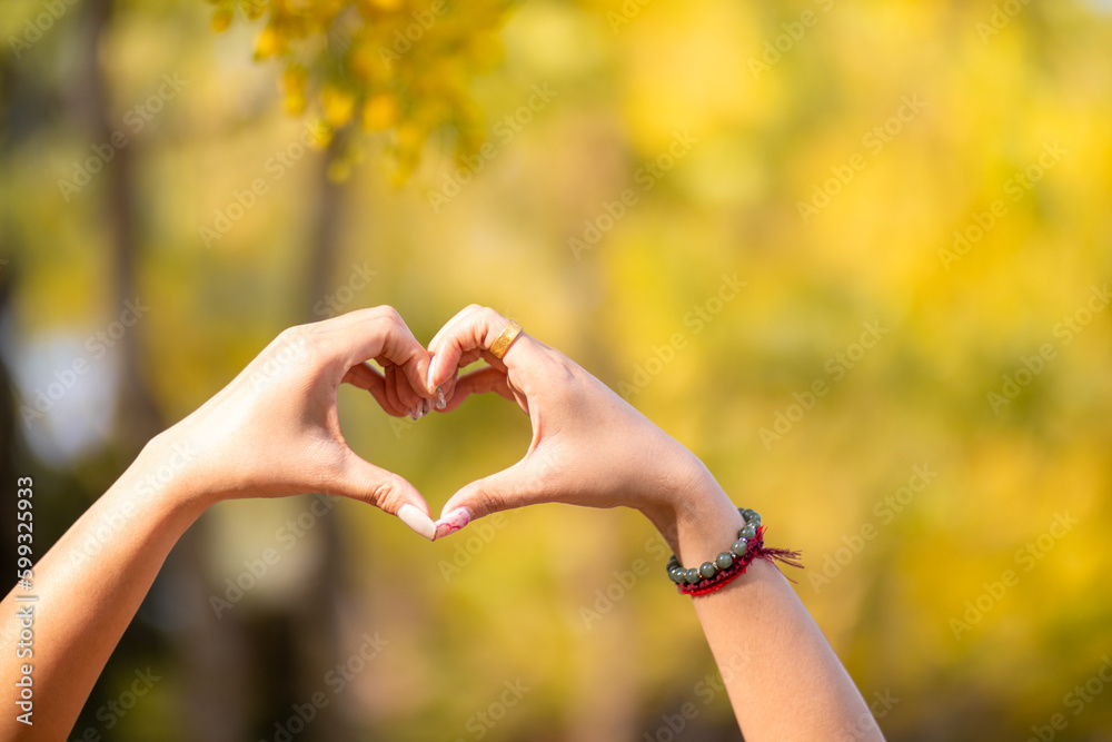 woman holds her hand above her head to form heart symbol that represents love, friendship and kindness between lovers and friends. heart symbol is concept that represents friendship, love and kindness woman holds her hand above her head to form heart symbol that represents love, friendship and kindness between lovers and friends. heart symbol is concept that represents friendship, love and kindness