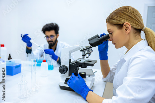 Researchers man and woman working with lab microscope for research project hospital laboratory room