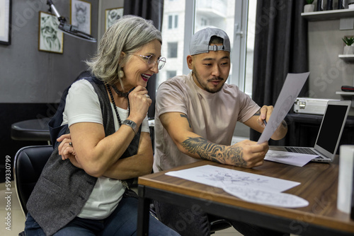Grey-haired woman sitting with a tattoo master