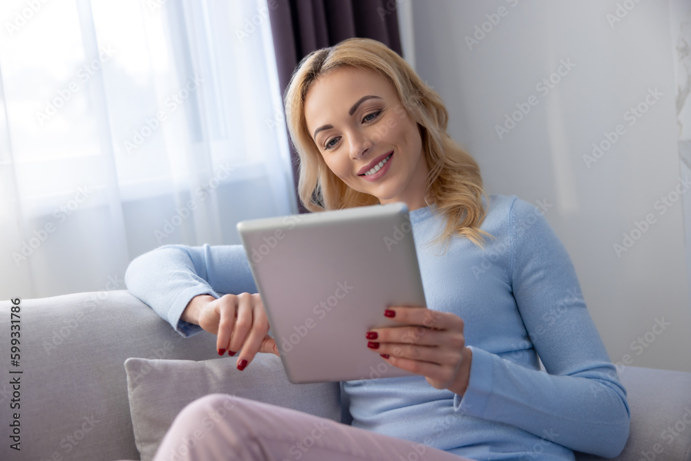 Contented blonde lady reading something on her tablet computer Contented blonde lady reading something on her tablet computer