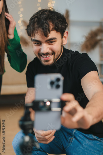 Young caucasian man having fun at home creating videos for his social media, together with his girlfriend. Making dance videos to share on social media. Happy