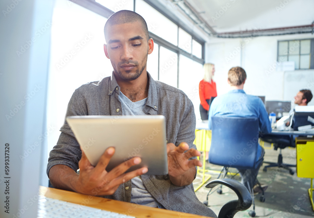 Hes the consummate young professional. a designer using a digital tablet while working in an office.