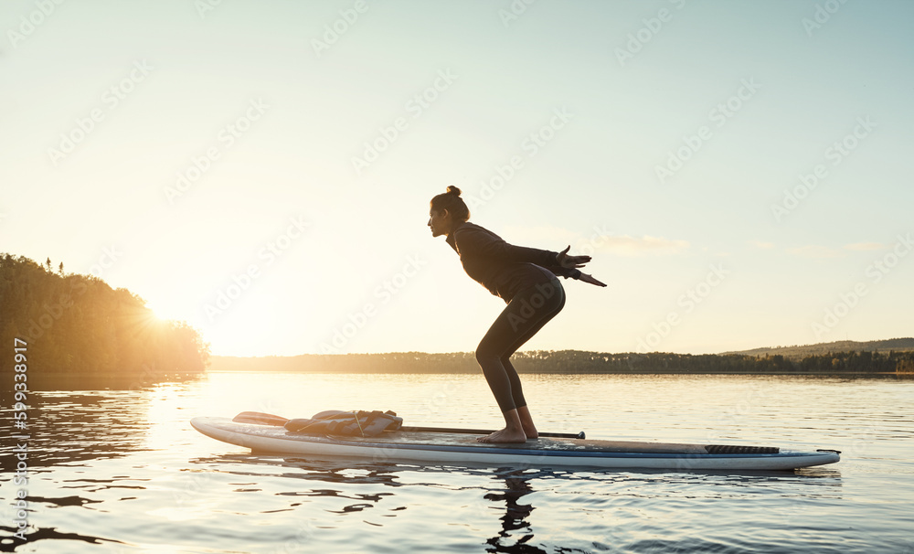 Its all about balance and strength. an attractive young woman doing yoga on a paddle board on a lake outdoors.