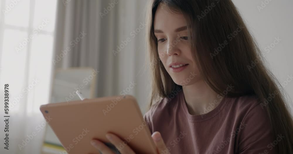 Slow motion portrait of happy woman illustrator using graphics tablet drawing and smiling at home. Enjoyable occupation and technology concept.