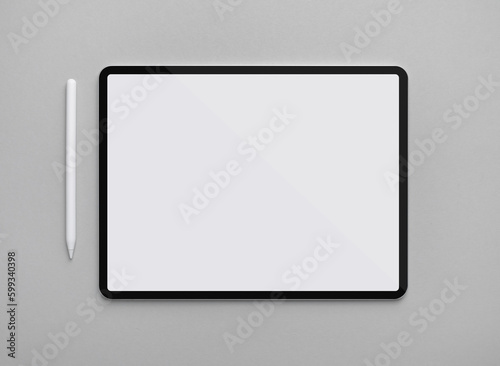 Digital tablet with blank white screen and stylus pen on gray paper background. Flat lay.