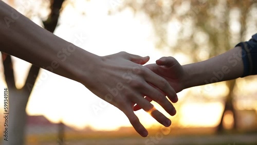 Cropped shot of adult man and child hands shaking in sunlight against sunset. Teamwork between dad and son. Strong family ties concept. Father with kid greeting each other with a firm handshake.