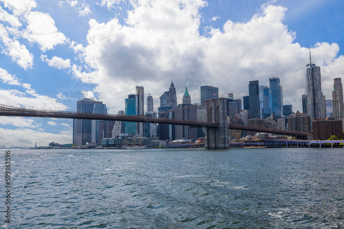 Gorgeous view of Manhattan skyscrapers and Brooklyn Bridge against blue sky with white clouds. New York.  © Alex