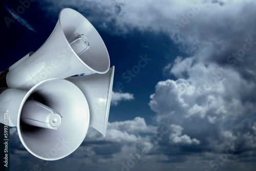 Loudhailer or megaphone. Siren, air raid alert, public hearing concept. Sky, clouds, storm with loudspeaker. photo
