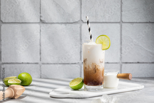 Trendy authentic dirty soda cocktail with cola, lime juice and cream in the kitchen table