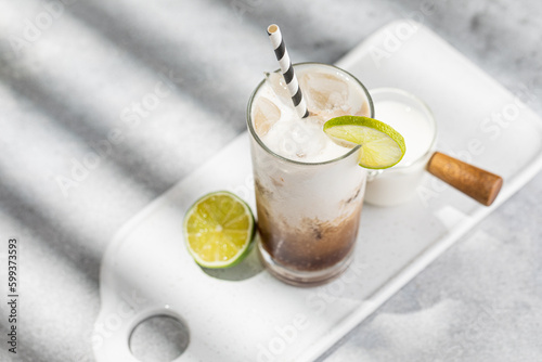 Trendy authentic dirty soda cocktail with cola, lime juice and cream in the kitchen table, top view