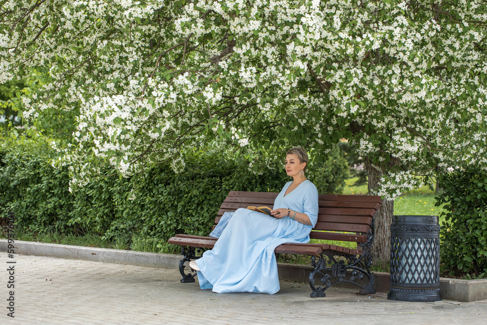 Portrait of a middle-aged woman in a blue dress sits on a bench Portrait of a middle-aged woman in a blue dress sits on a bench