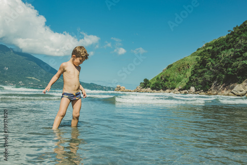 Menino brincando no mar da praia © Danielle