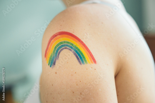 Rainbow painted on a woman's shoulder, happy pride month