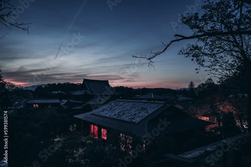 The charm of Kyoto's traditional houses is amplified by the beautiful cherry blossoms and a spectacular sunset sky