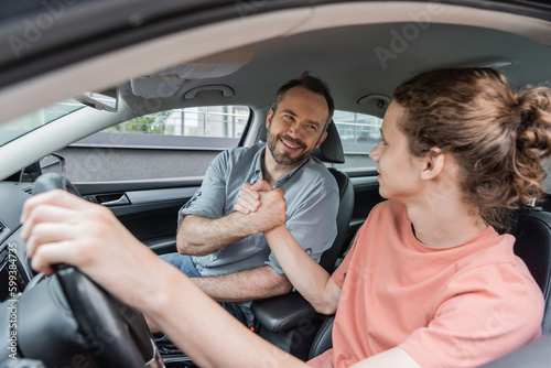 happy father and son shaking hands while sitting together in car.