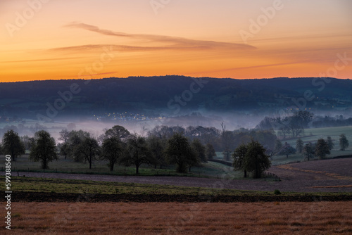 Colourful sunrise on a summer morning with a little fog on the ground and spectacular views over the Dutch hillside near the village of Kuttingen photo