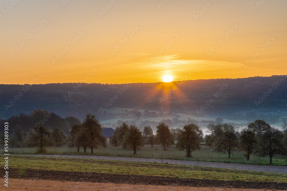 Fototapeta premium Colourful sunrise on a summer morning with a little fog on the ground and spectacular views over the Dutch hillside near the village of Kuttingen