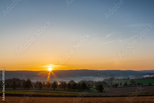 Colourful sunrise on a summer morning with a little fog on the ground and spectacular views over the Dutch hillside near the village of Kuttingen