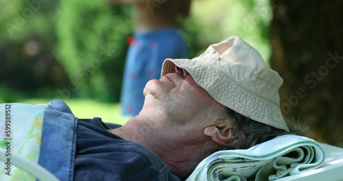 Grand-father sleeping outside resting with face covered with hat