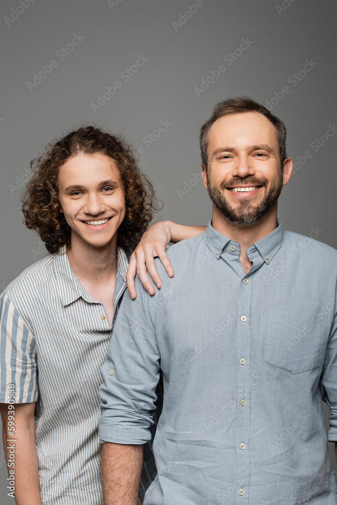 happy father and son in shirts looking at camera and smiling isolated on grey. happy father and son in shirts looking at camera and smiling isolated on grey.