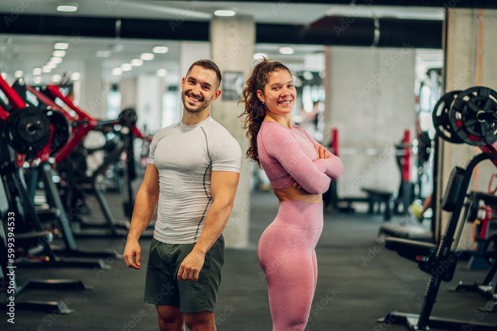 Obraz premium Happy sporty friends in sportswear are confidently standing in a gym and smiling at the camera.