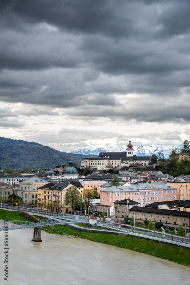 View on Salzburg in the Austrian Alps with the city castle on a hill, the Salzach river and stormy clouds 