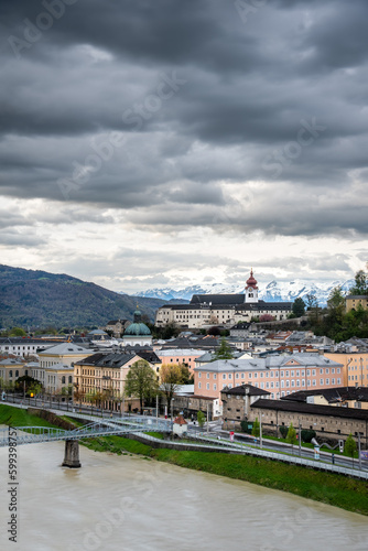 View on Salzburg in the Austrian Alps with the city castle on a hill, the Salzach river and stormy clouds 