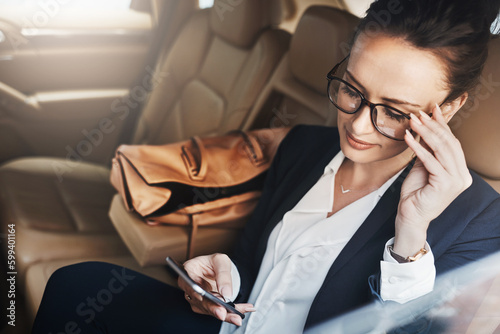 Just another work day. a confident young businesswoman seated in a car as a passenger while texting on her phone on her way to work.