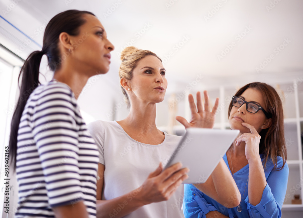 Sharing a collective vision. Three businesswomen brainstorming ideas while gathered around a digital tablet. Sharing a collective vision. Three businesswomen brainstorming ideas while gathered around a digital tablet.