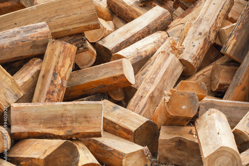 A pile of chopped wood for a fire as a background. Chopped tree trunks are thrown in a chaotic order on top of each other in close-up. A pile of chopped wood for a fire as a background. Chopped tree trunks are thrown in a chaotic order on top of each other in close-up.