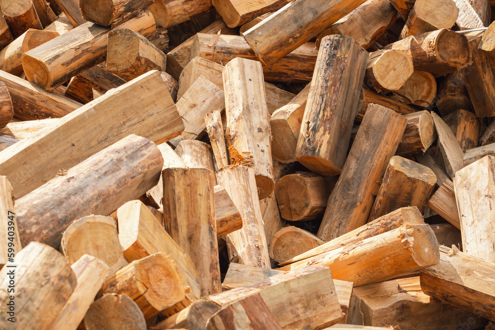 A pile of chopped wood for a fire as a background. Chopped tree trunks are thrown in a chaotic order on top of each other in close-up. A pile of chopped wood for a fire as a background. Chopped tree trunks are thrown in a chaotic order on top of each other in close-up.