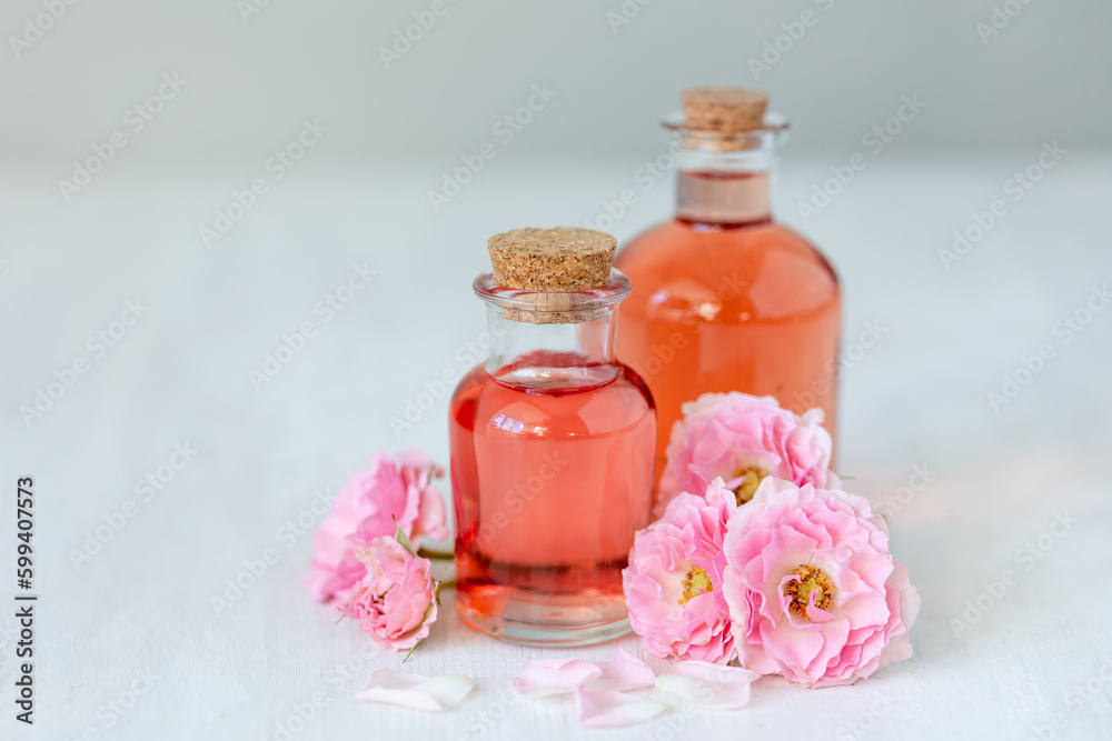 Concept of perfume with pure natural organic rose ingredient, essential oils. Glass bottles with flower herbal extract and elixir. Perfumery cosmetic toilet water fragrance, cream, skin care product