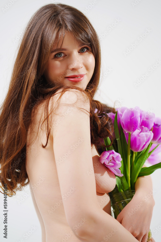 a gentle woman topless with tulips on a white background.