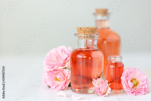 Composition with pure natural organic rose essential oil in glass bottle  luxury perfumery ingredient for premium fragrance  skin care products  anti-age beauty treatment. Fresh flowers