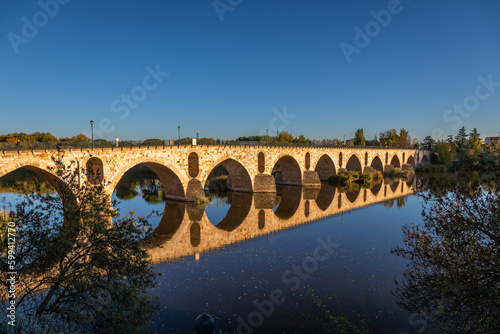 Beautiful panoramic view of Zamora roman bridge called Puente de Piedra, just before sunset, during Autumn season, on the Douro River, in Spain.