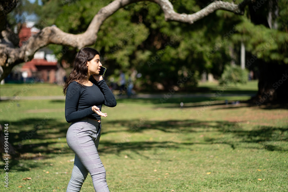 Latin teen girl talking on the phone in a park