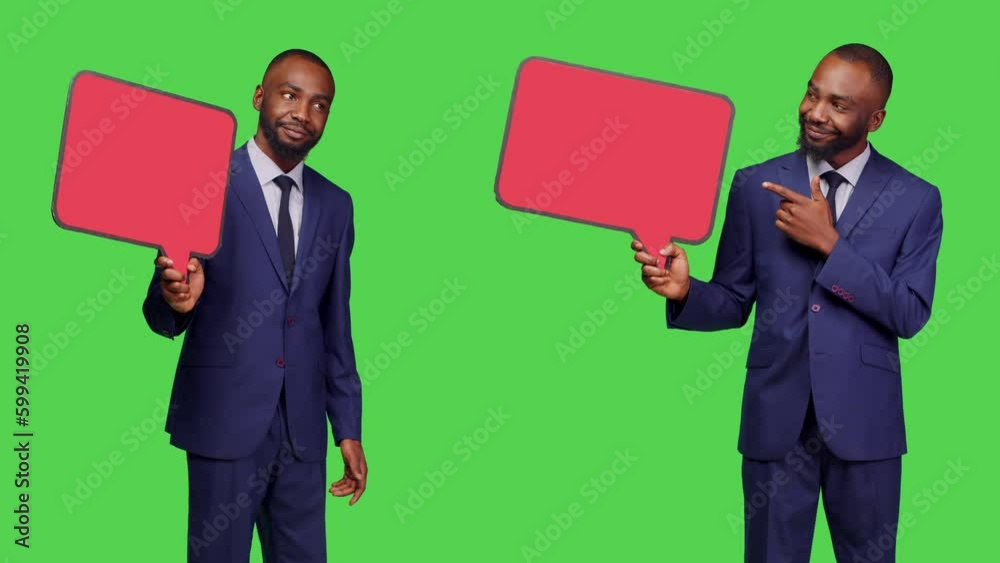 Startup worker holding empty speech bubble on camera, creating advertisement with blank isolated copyspace billboard. Male company employee wearing office suit over greenscreen backdrop. Startup worker holding empty speech bubble on camera, creating advertisement with blank isolated copyspace billboard. Male company employee wearing office suit over greenscreen backdrop.