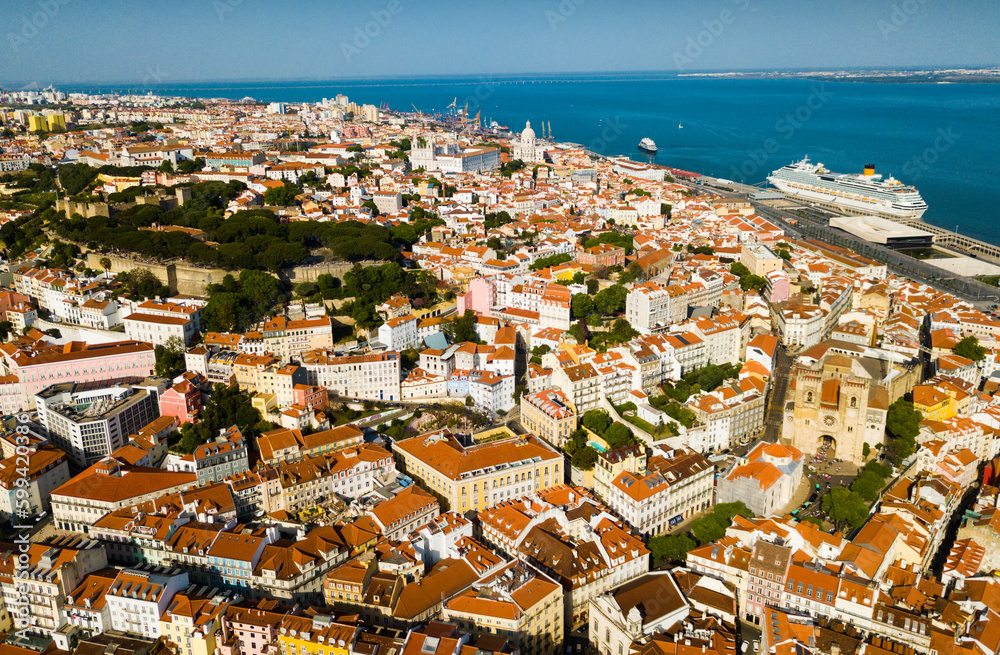 Picturesque aerial view of historical areas of Lisbon on bank of Tagus river overlooking medieval Roman Catholic Cathedral, Portugal